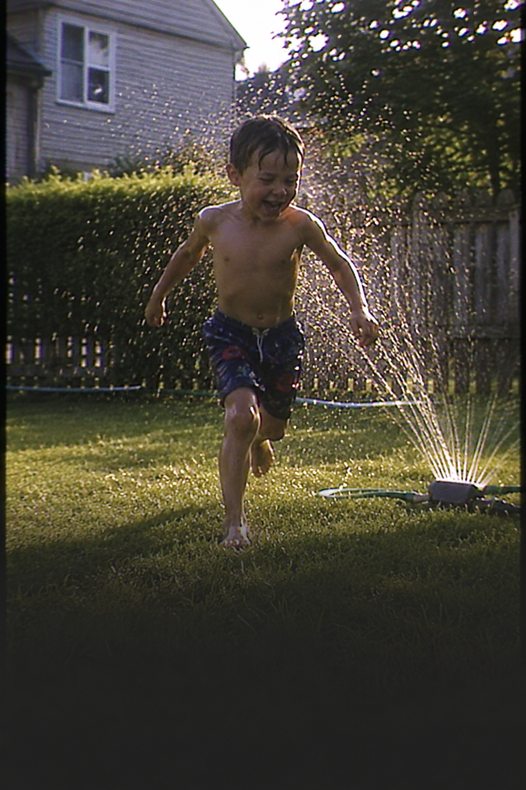 A nostalgic camcorder-style preview of a child running through sprinklers.